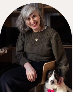Portrait de Claudia Patrignani, architecte d’intérieur à Lyon, souriante dans son univers de travail, accompagnée de son chien